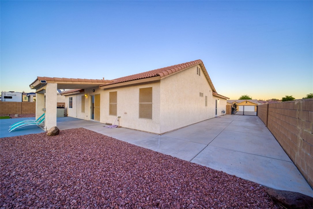 2213 Jamie Road Fort Mohave, AZ 86426 - Photo 39 of 51 Back of house at dusk featuring a fenced backyard, a patio, stucco siding, and a tile roof
