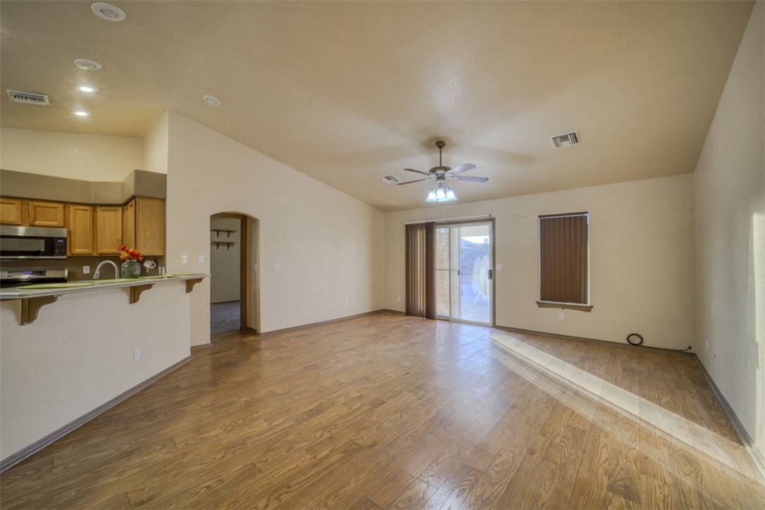 2213 Jamie Road Fort Mohave, AZ 86426 - Photo 8 of 51 Unfurnished living room featuring dark wood finished floors, vaulted ceiling, arched walkways, and ceiling fan