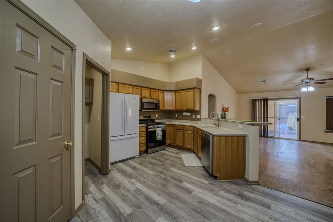 2213 Jamie Road Fort Mohave, AZ 86426 - Photo 10 of 51 Kitchen featuring stainless steel appliances, vaulted ceiling, brown cabinetry, a peninsula, and light countertops