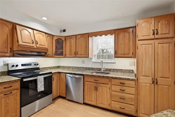 a kitchen with granite countertop cabinets stainless steel appliances a sink and window