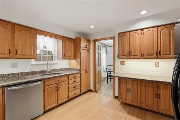 a kitchen with stainless steel appliances granite countertop a refrigerator a sink dishwasher and wooden cabinets with wooden floor