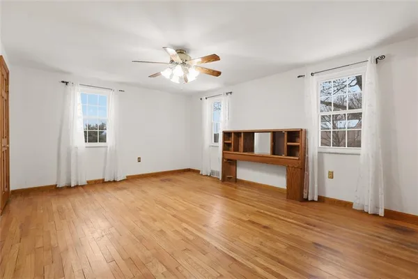 a view of an empty room with window and wooden floor