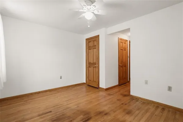 an empty room with wooden floor closet fan and windows