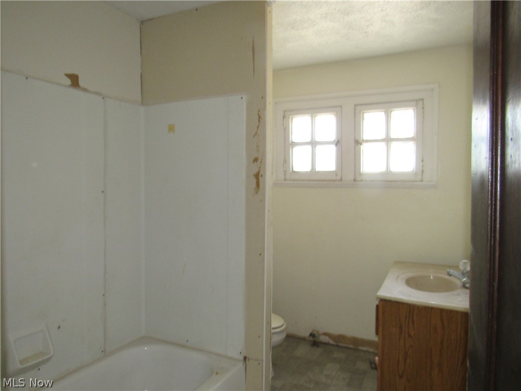 1726 Lee Road Cleveland Heights, OH 44118 - Photo 22 of 36 Bathroom featuring a built-in tub with a white surround, double-paned window, vanity with a light-colored countertop and integrated sink, and wood-finish cabinetry
