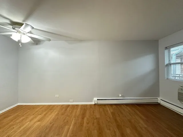 a view of an empty room with window and wooden floor