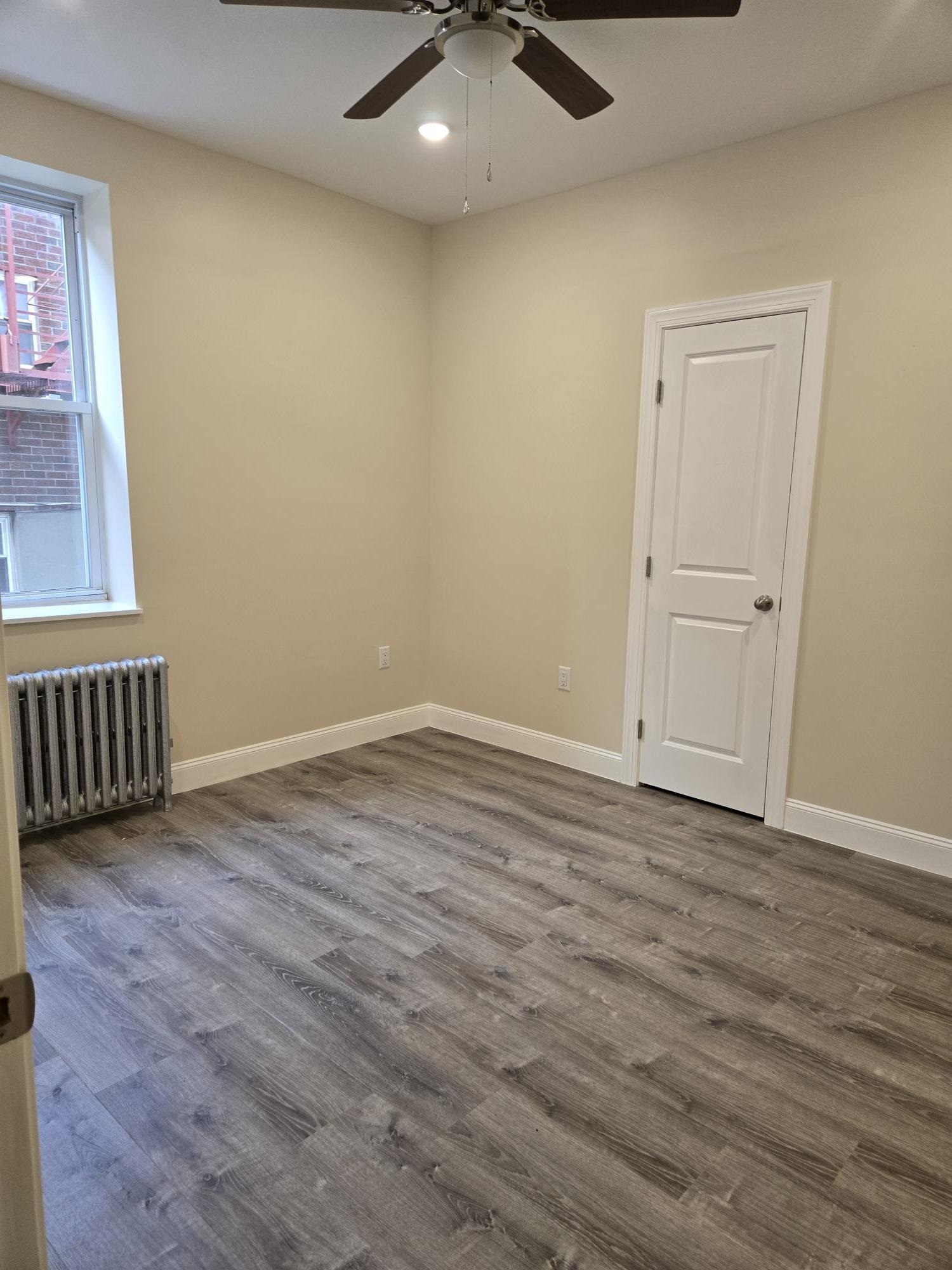 289 Day Avenue, Unit A2 Fairview, NJ 07022 - Photo 4 of 6 an empty room with wooden floor fan and windows