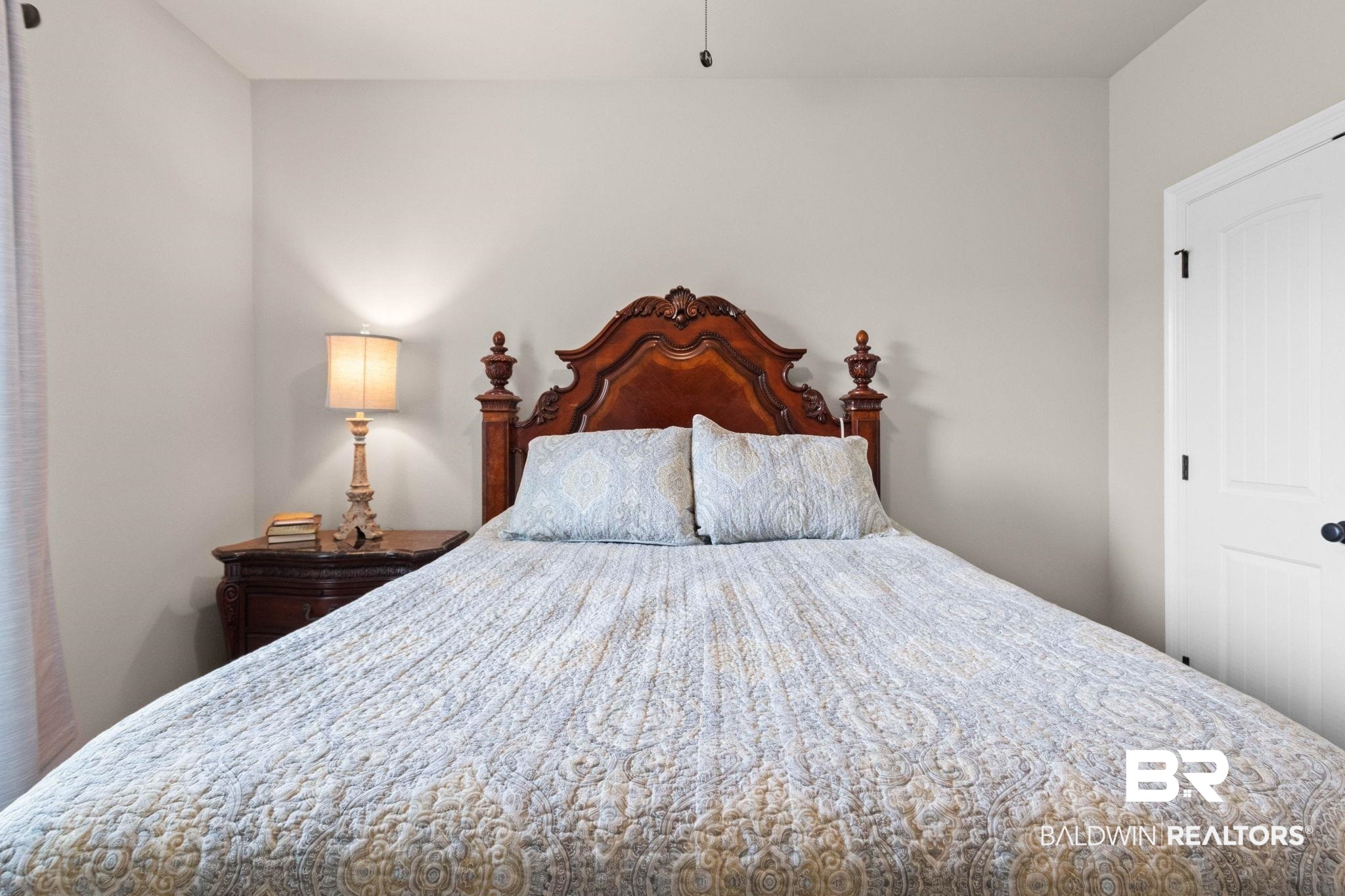 22244 Hibiscus Circle Foley, AL 36535 - Photo 36 of 51 Bedroom featuring a carved wood-finish headboard, light neutral wall paint, and a white paneled door with black hardware