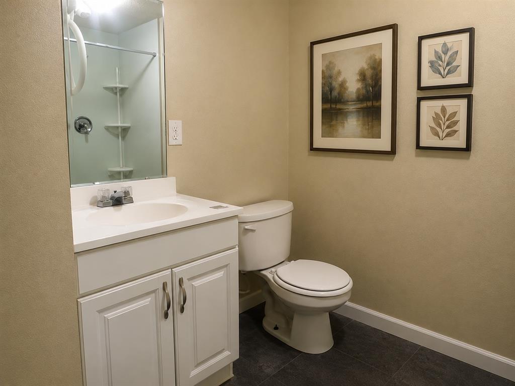 511 Rogers Road Newark, TX 76071 - Photo 20 of 22 Bathroom featuring a white vanity with integrated sink, chrome faucet, white paneled cabinetry, and a white toilet