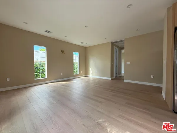 a view of an empty room with wooden floor and windows