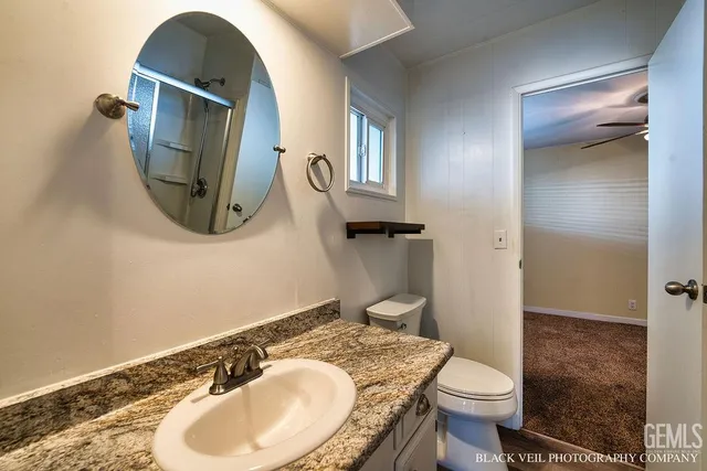 a bathroom with a granite countertop toilet sink and mirror