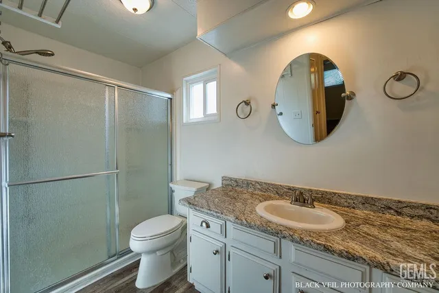a bathroom with a granite countertop sink a toilet and a mirror
