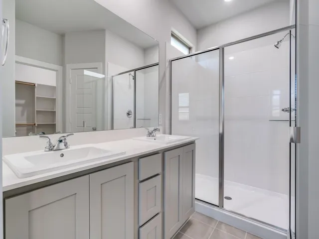 a bathroom with a double vanity sink mirror and shower