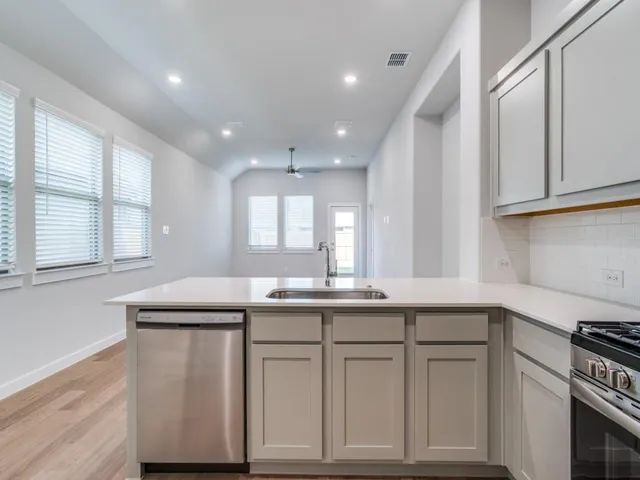 a kitchen with white cabinets and sink
