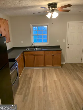 a kitchen with granite countertop a sink cabinets stainless steel appliances and a window