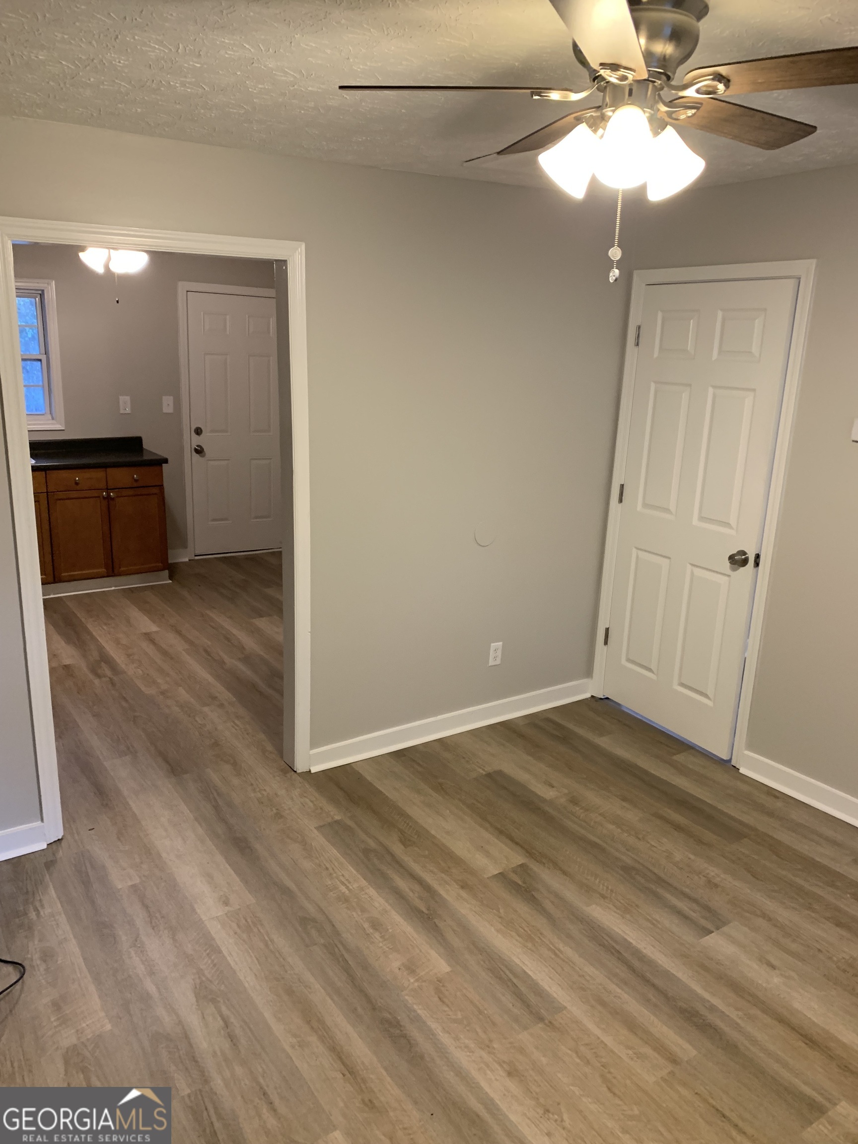 7181 Puckett Street Southwest Covington, GA 30014 - Photo 9 of 18 a view of an empty room with wooden floor and a ceiling fan