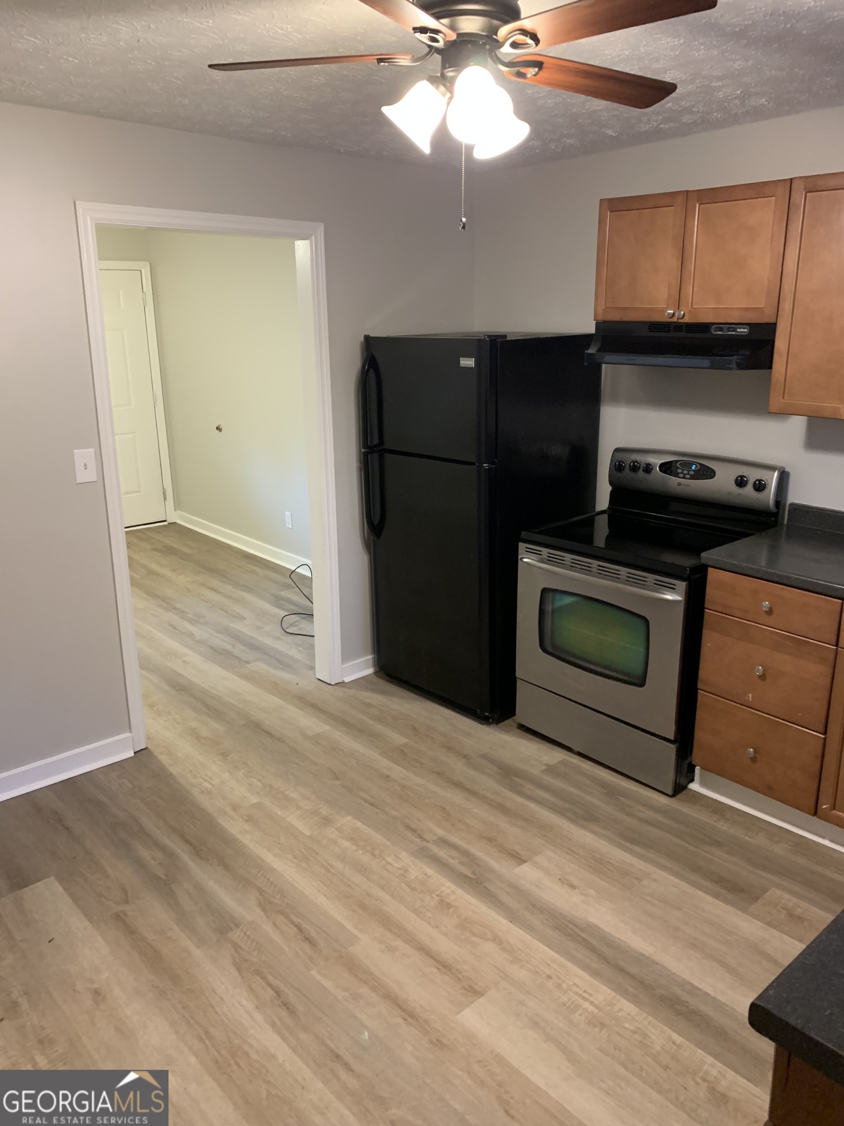 7181 Puckett Street Southwest Covington, GA 30014 - Photo 10 of 18 a kitchen with stainless steel appliances granite countertop a refrigerator a stove and a sink with wooden floor