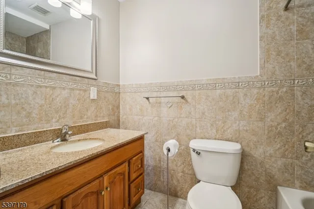a bathroom with a granite countertop toilet sink and mirror