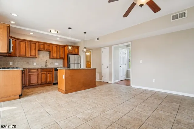 a kitchen with stainless steel appliances kitchen island granite countertop a refrigerator a stove top oven and white cabinets