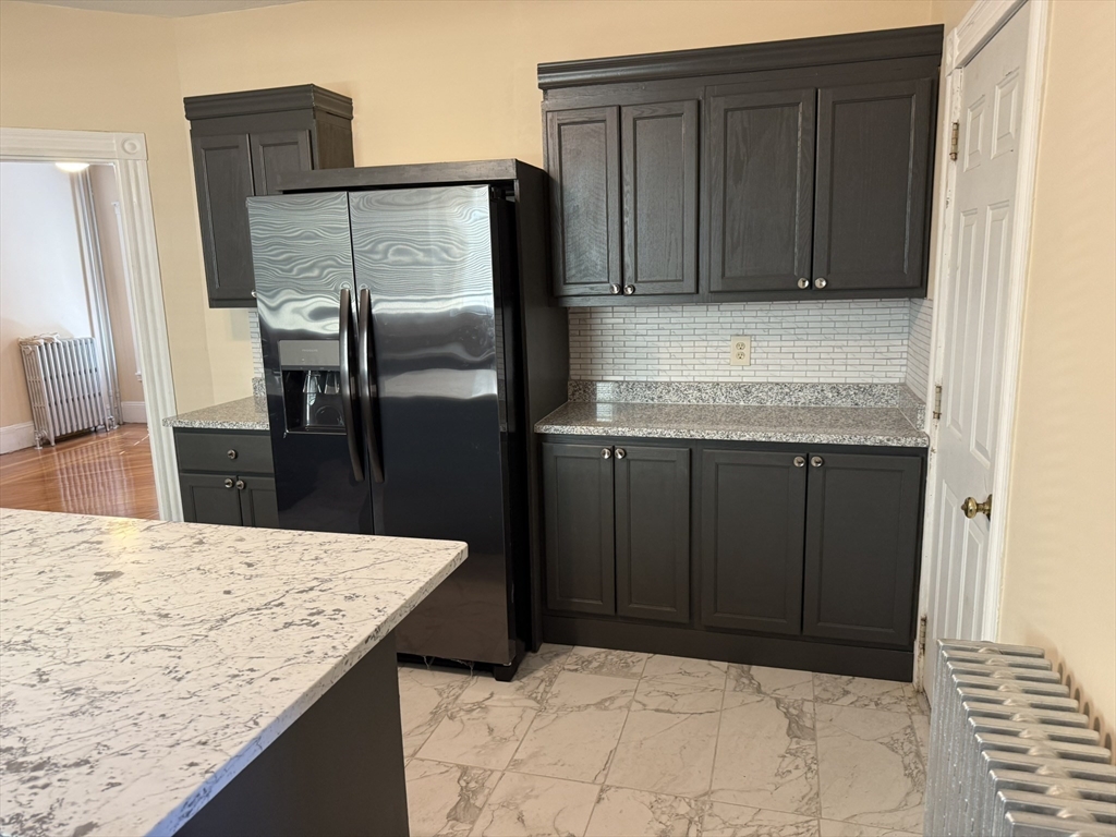 4 Dever Street, Unit 1 Boston, MA 02122 - Photo 7 of 22 a kitchen with granite countertop wooden cabinets and refrigerator