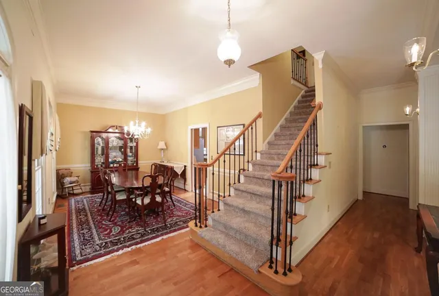 a view of a livingroom with furniture stairs wooden floor and windows