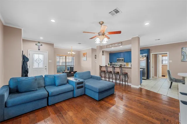 a living room with furniture kitchen view and a wooden floor