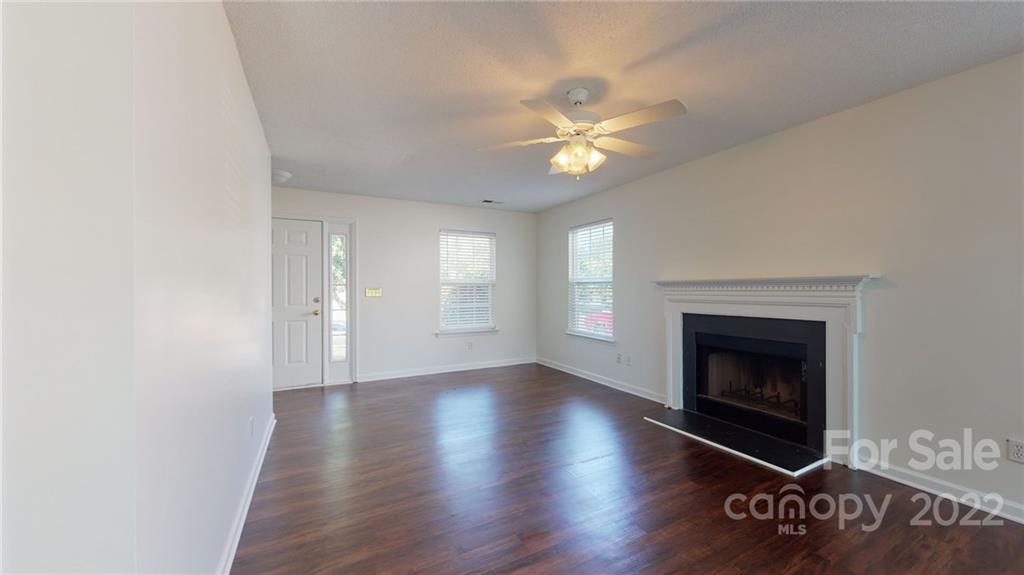 8821 Cameron Spring Road Charlotte, NC 28214 - Photo 12 of 40 an empty room with windows fireplace and wooden floor