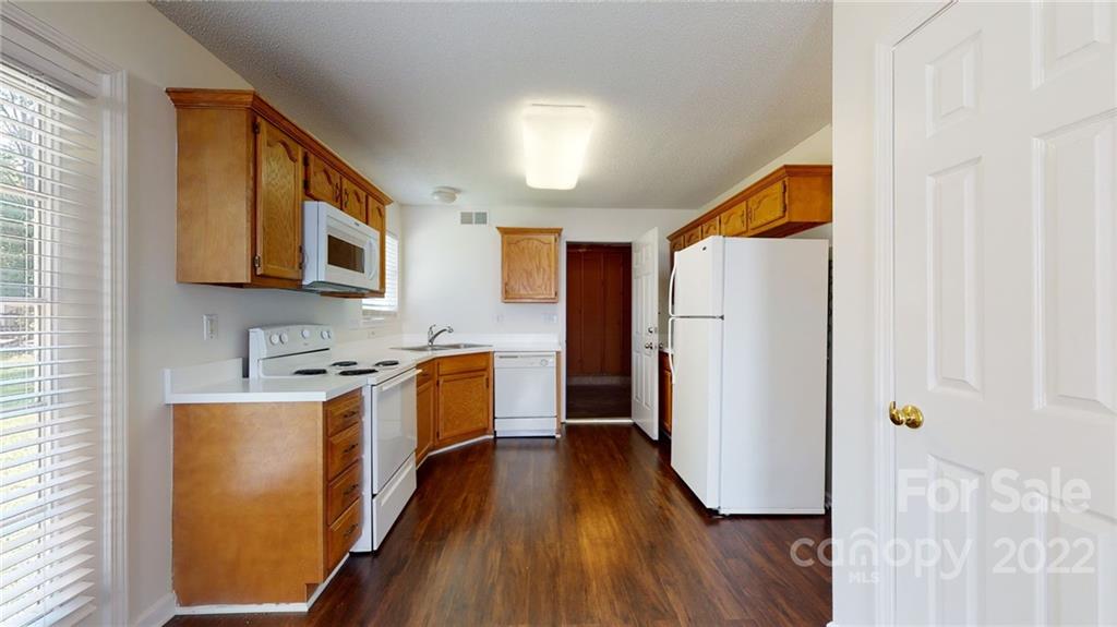 8821 Cameron Spring Road Charlotte, NC 28214 - Photo 13 of 40 a kitchen with stainless steel appliances granite countertop a refrigerator a sink dishwasher and wooden cabinets with wooden floor