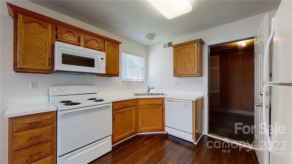 8821 Cameron Spring Road Charlotte, NC 28214 - Photo 14 of 40 a kitchen with stainless steel appliances granite countertop wooden cabinets a stove a sink and a microwave