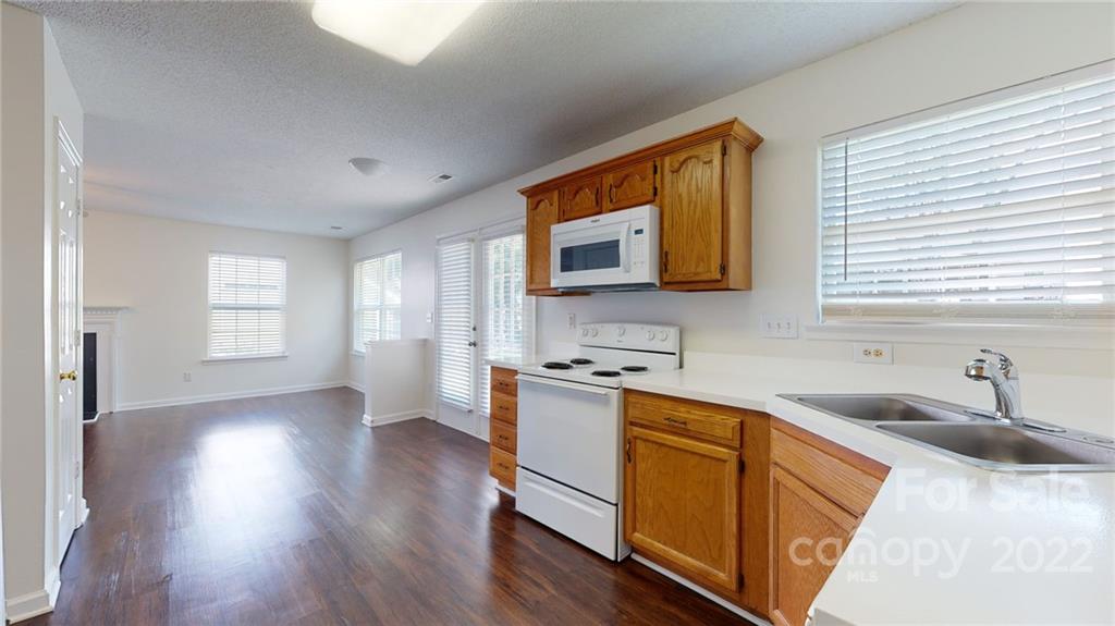 8821 Cameron Spring Road Charlotte, NC 28214 - Photo 18 of 40 a kitchen with stainless steel appliances granite countertop a sink a stove a refrigerator wooden floor and cabinets