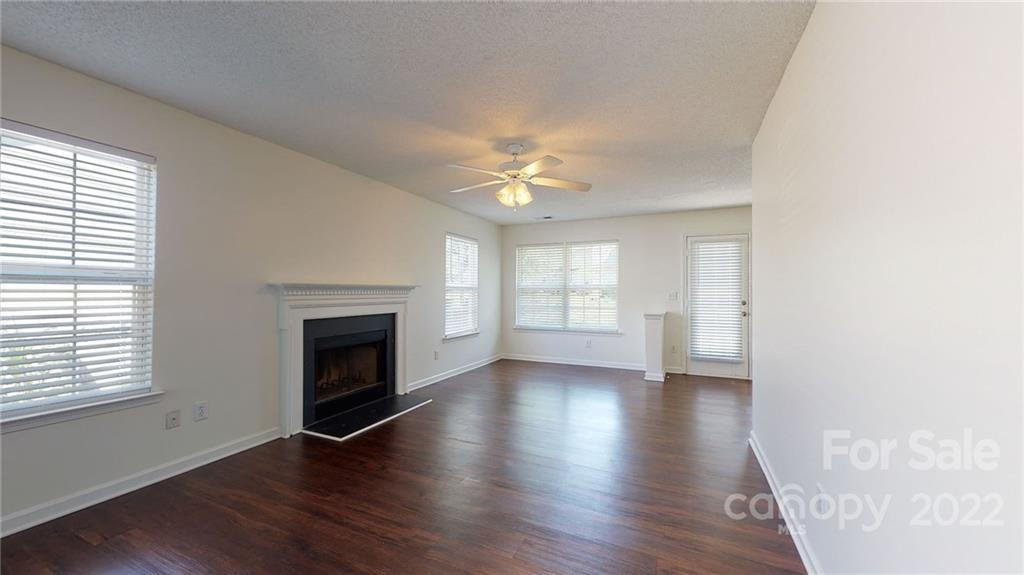 8821 Cameron Spring Road Charlotte, NC 28214 - Photo 6 of 40 an empty room with wooden floor fireplace and windows