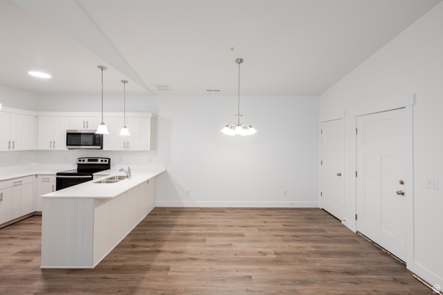 4661 Poplar Way, Unit R301 Mapleton, UT 84664 - Photo 13 of 17 Kitchen featuring white cabinets, a peninsula, range with electric stovetop, dark wood-style flooring, and suspended lighting