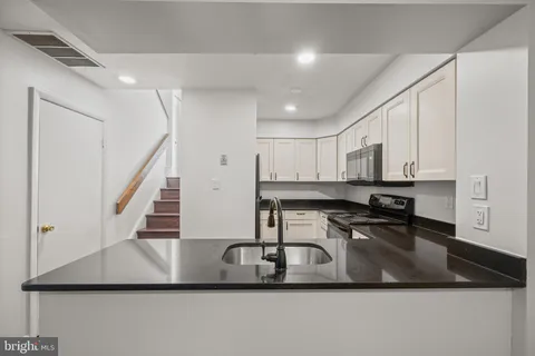 a kitchen with a sink a stove and white cabinets