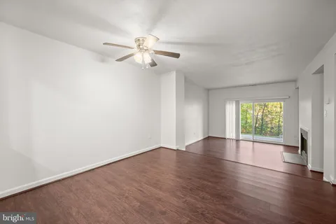 an empty room with wooden floor chandelier fan and windows