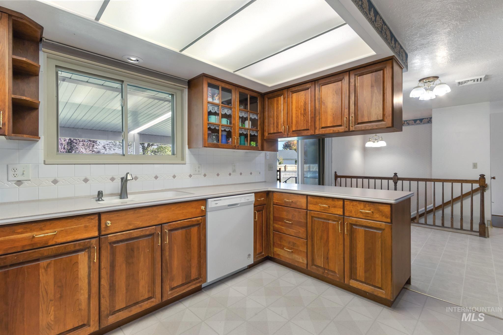 11360 West Lake Hazel Road Boise, ID 83709 - Photo 20 of 50 Tile flooring, built-in microwave, wood-finish cabinetry, white appliances, and a solid surface countertop