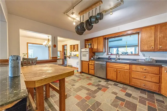 a kitchen with stainless steel appliances granite countertop wooden cabinets a refrigerator a sink a stove and island