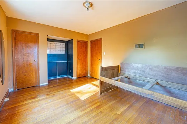 a view of kitchen and empty room with wooden floor