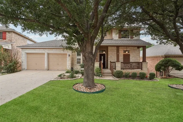 a front view of a house with a garden and tree