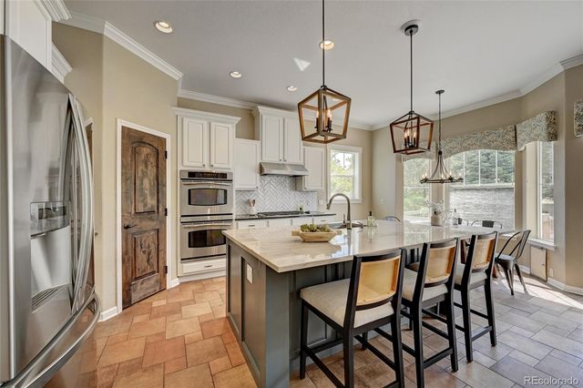 a kitchen with stainless steel appliances granite countertop a sink a stove a refrigerator and island