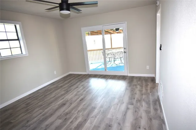 an empty room with wooden floor and windows