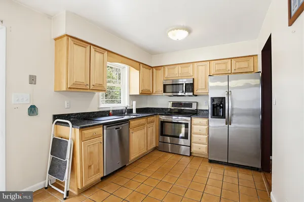 a kitchen with stainless steel appliances granite countertop a stove a sink a dining table and chairs