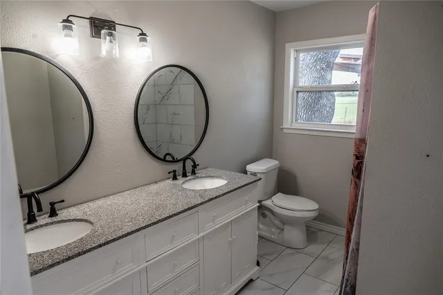 a bathroom with a granite countertop toilet a sink and a mirror