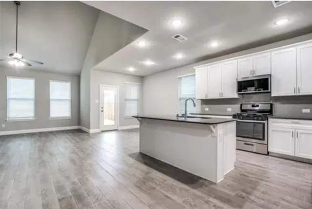 a kitchen with granite countertop a stove top oven a sink dishwasher and a refrigerator with wooden floor