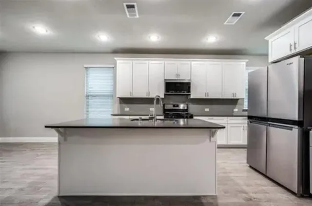 a kitchen with stainless steel appliances a refrigerator a sink a stove a microwave a sink and cabinets