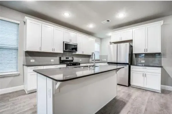 a kitchen with stainless steel appliances granite countertop a sink stove microwave and refrigerator