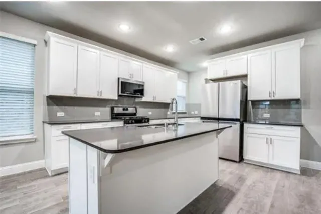 a kitchen with stainless steel appliances granite countertop a sink stove microwave and refrigerator