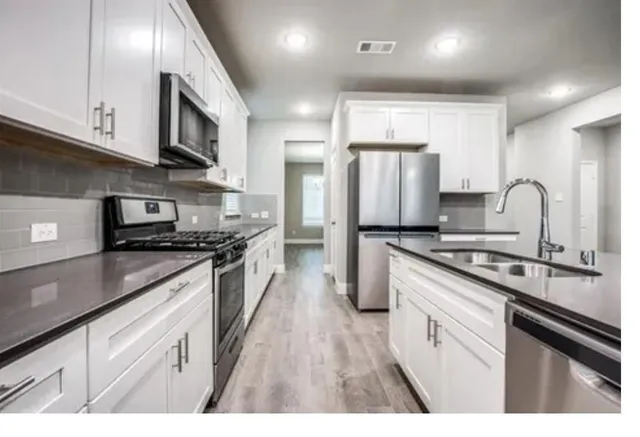 a kitchen with stainless steel appliances granite countertop a sink a stove and a refrigerator