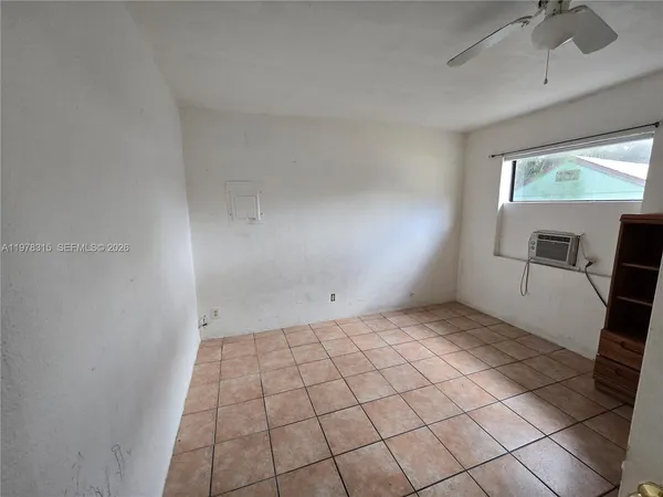a view of an empty room and kitchen with windows
