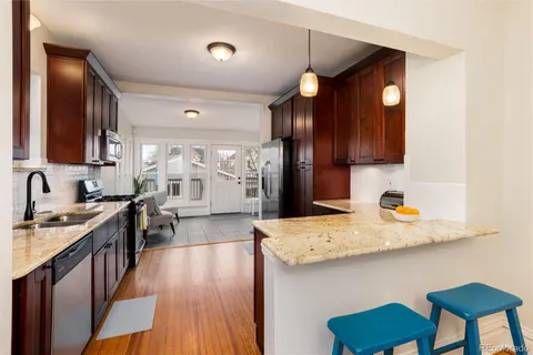 a kitchen with stainless steel appliances granite countertop hardwood floor sink stove dining table and chairs