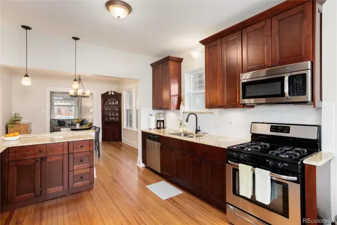 a kitchen with stainless steel appliances granite countertop a refrigerator a stove and a sink