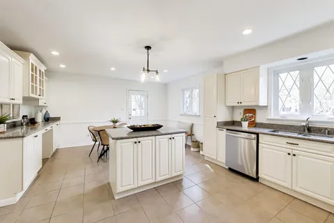 a kitchen with kitchen island granite countertop a sink counter top space appliances and cabinets